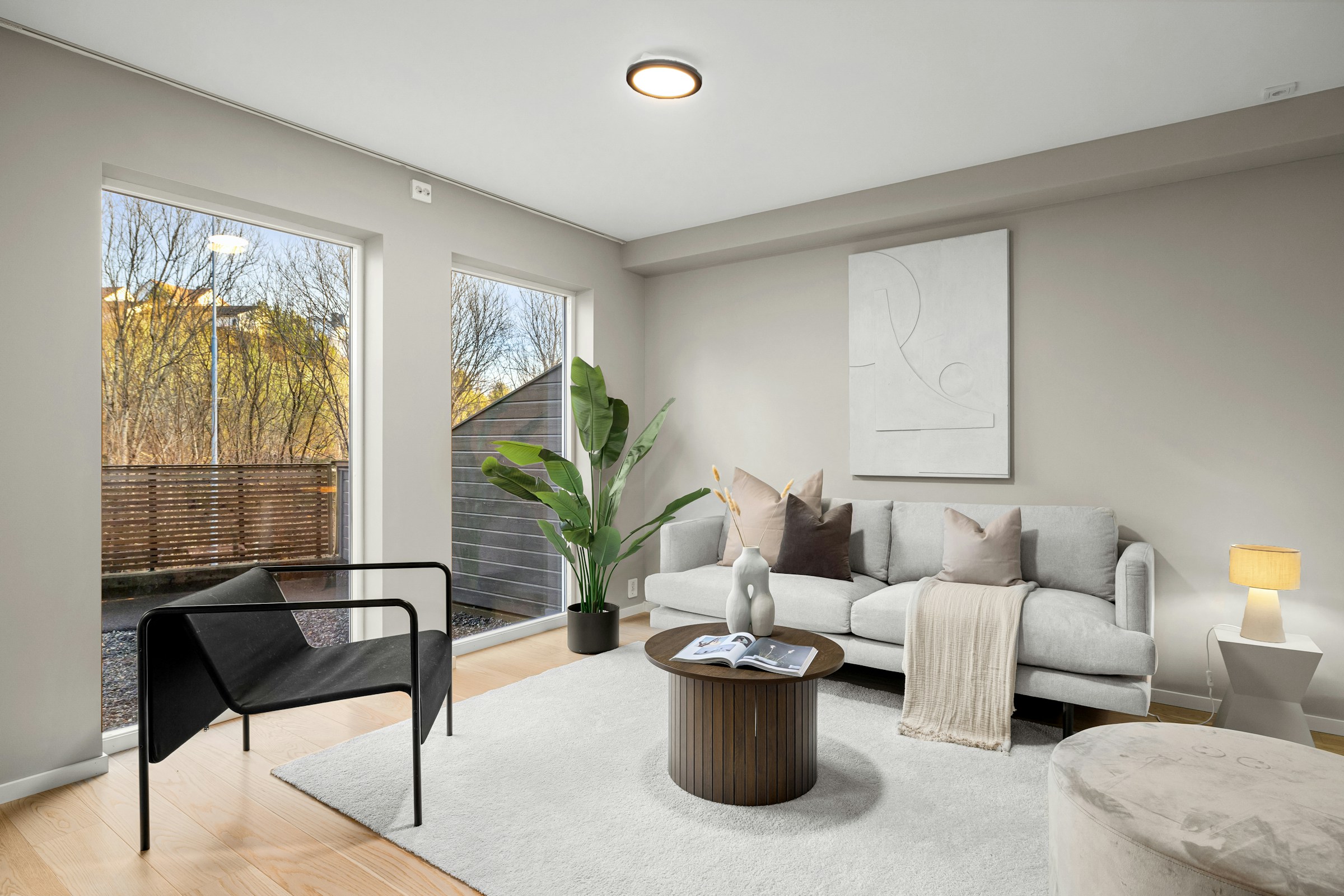 A bright, comfortable living room with large windows and natural greenery